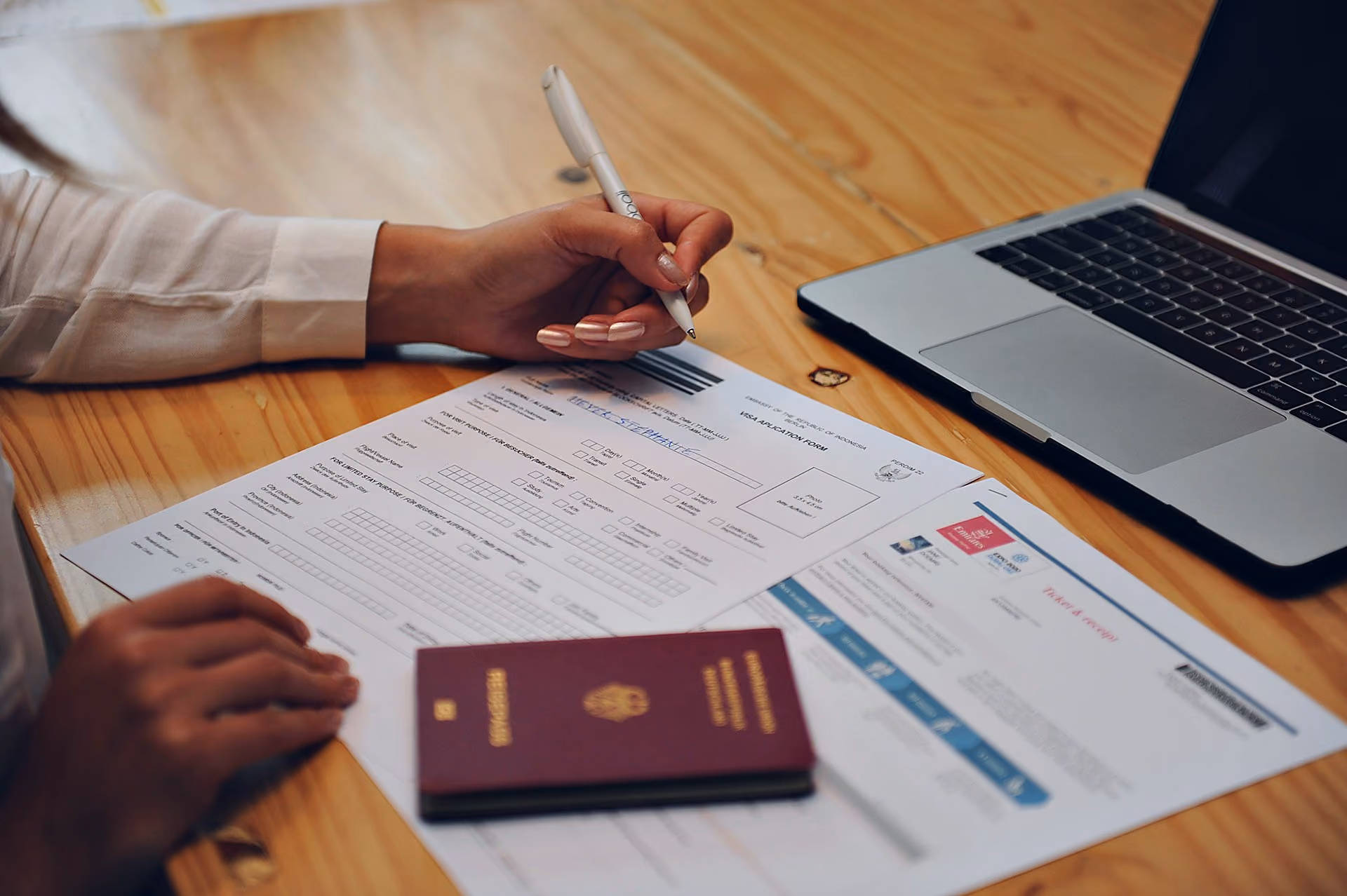 Student fyller ut visumpapirer for å studere på Bali, med et pass på bordet